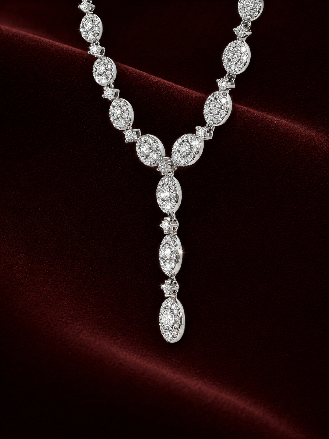 Front-facing ENS5756 oval diamond drop necklace on naturally draped deep burgundy velvet